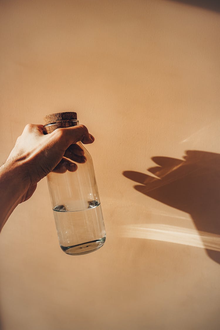 Crop Person Holding Glass Bottle Of Water