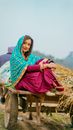 Positive young ethnic woman riding on wooden wagon in village