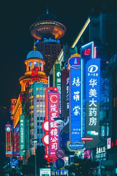 Colorful illuminated signs and bustling nightlife on Nanjing Road, Shanghai at night, showcasing urban vibrancy.