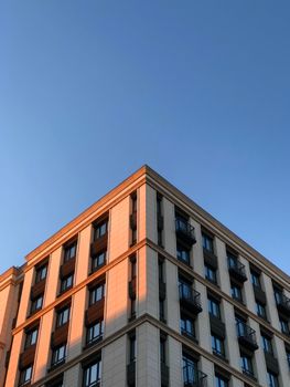 From below of contemporary building corner with strict geometry against cloudless blue sky