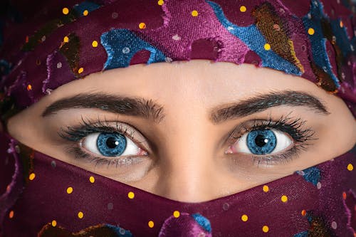 보라색 Hijab 스카프를 착용하는 파란 눈을 가진 여자