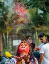 Indian woman with painted face throwing Holi paints in air