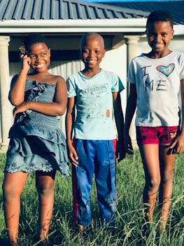 Three happy African children enjoying a sunny day outdoors in Mngungundlovu, South Africa.