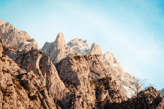 Breathtaking view of majestic, snow-capped mountain peaks under a clear blue sky, showcasing dramatic geological formations.