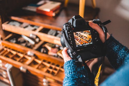 Crop faceless photographer taking photos of cabinet with craft tools