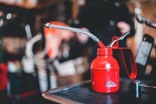 Red steel small ink bottle with pipe for retro printing machine placed on table in craftsmanship