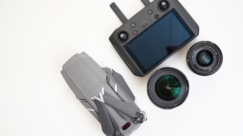 Top view of a drone, controller, and camera lenses on a white background.