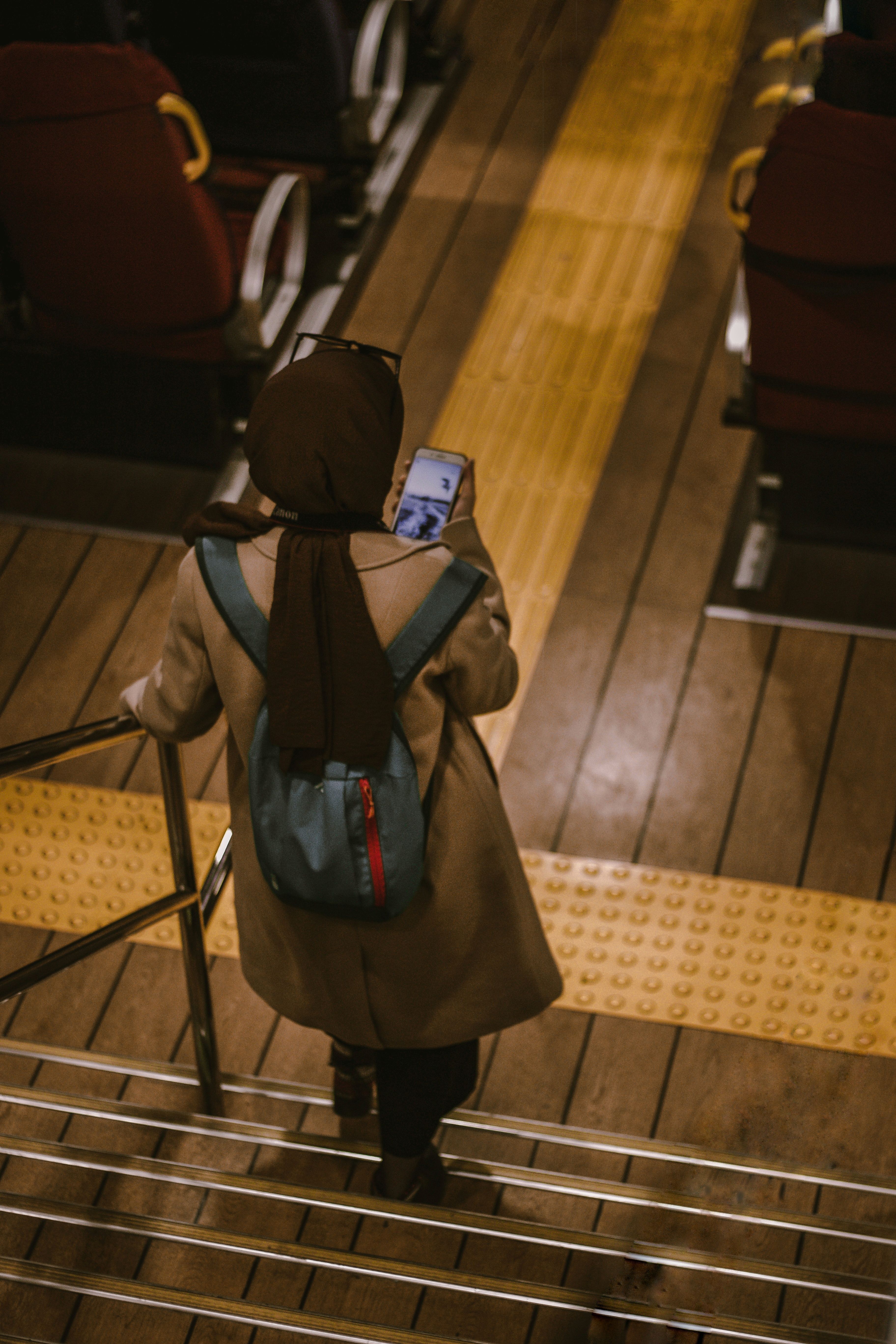 Back view of a woman with a backpack looking at a phone while descending stairs in Istanbul, Turkey. - Essential Items to Keep in Your Handbag