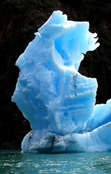 Stunning blue iceberg against a rugged backdrop in a serene natural setting.