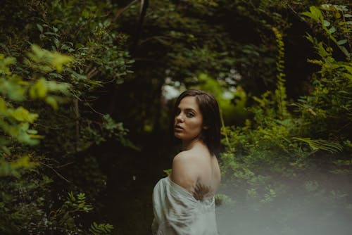 Free Woman in White Off Shoulder Dress Standing Near Green Plants Stock Photo