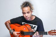 Focused ethnic male musician playing guitar in studio