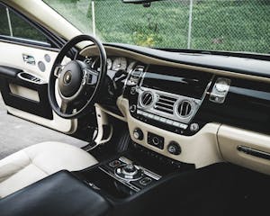 Expensive luxury car interior with white leather seats and shiny dashboard
