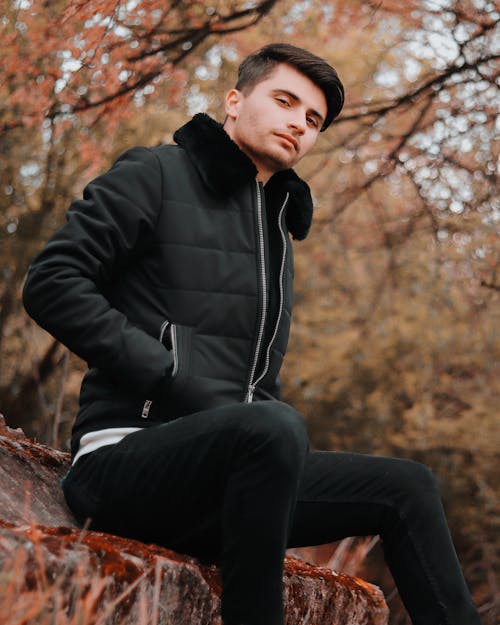 Pensive young man relaxing on bench in forest park