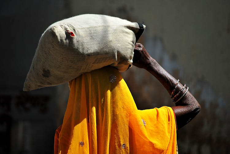 Anonymous Black Woman With Heavy Bag On Head