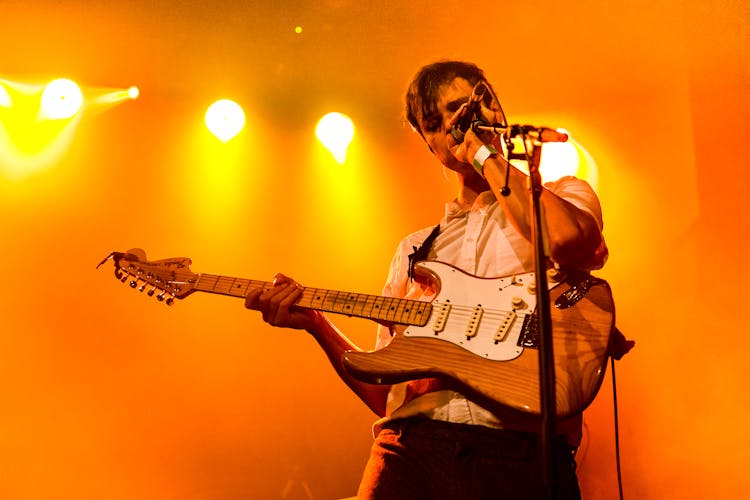 Young Man With Electric Guitar Singing On Stage