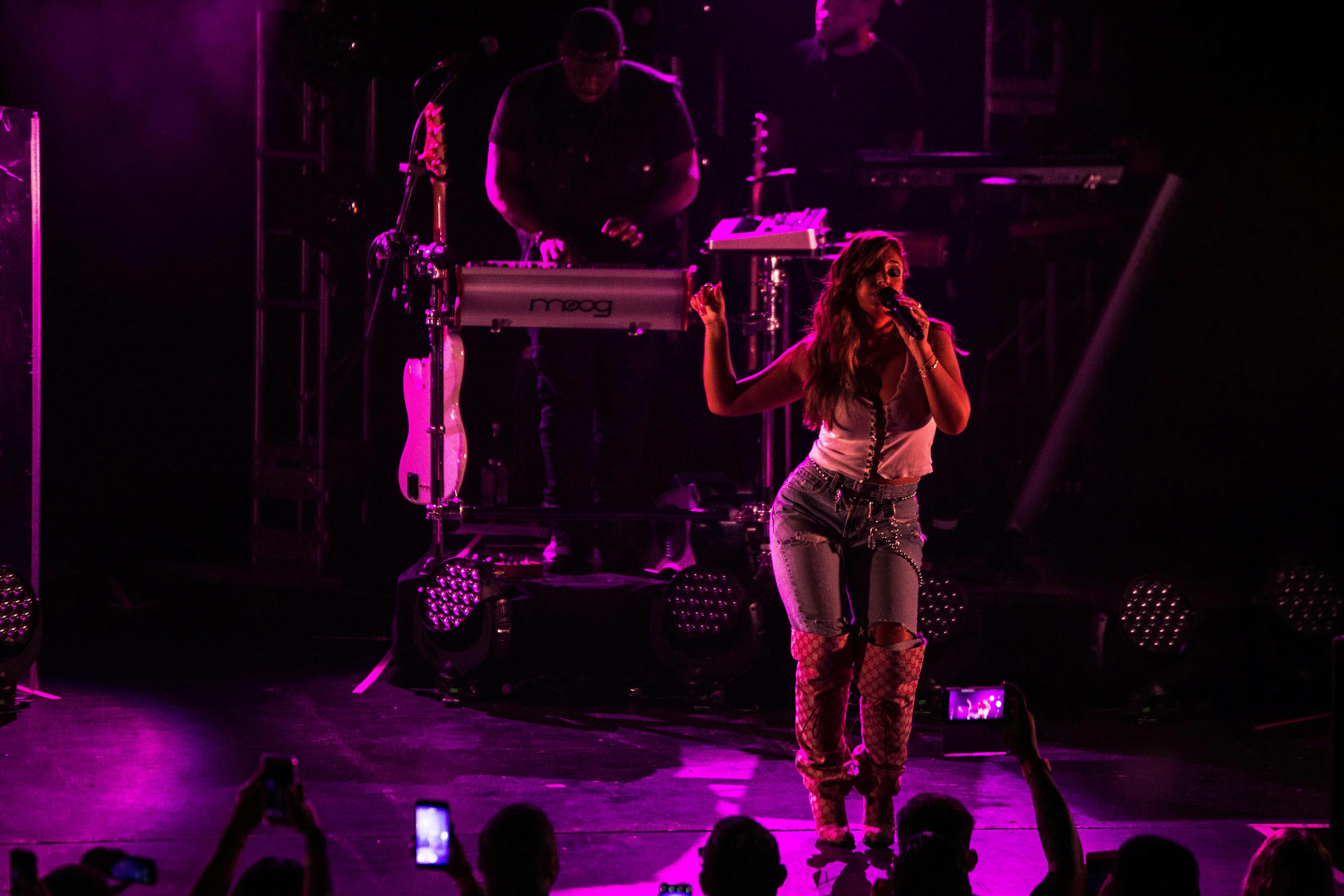 young female singer performing show on stage with neon lights