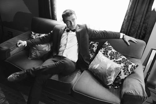 Black and White Photo of a Man Sitting on Sofa