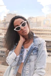 Woman in sunglasses and a denim jacket on a rooftop, by Léo Vinícius on Pexels