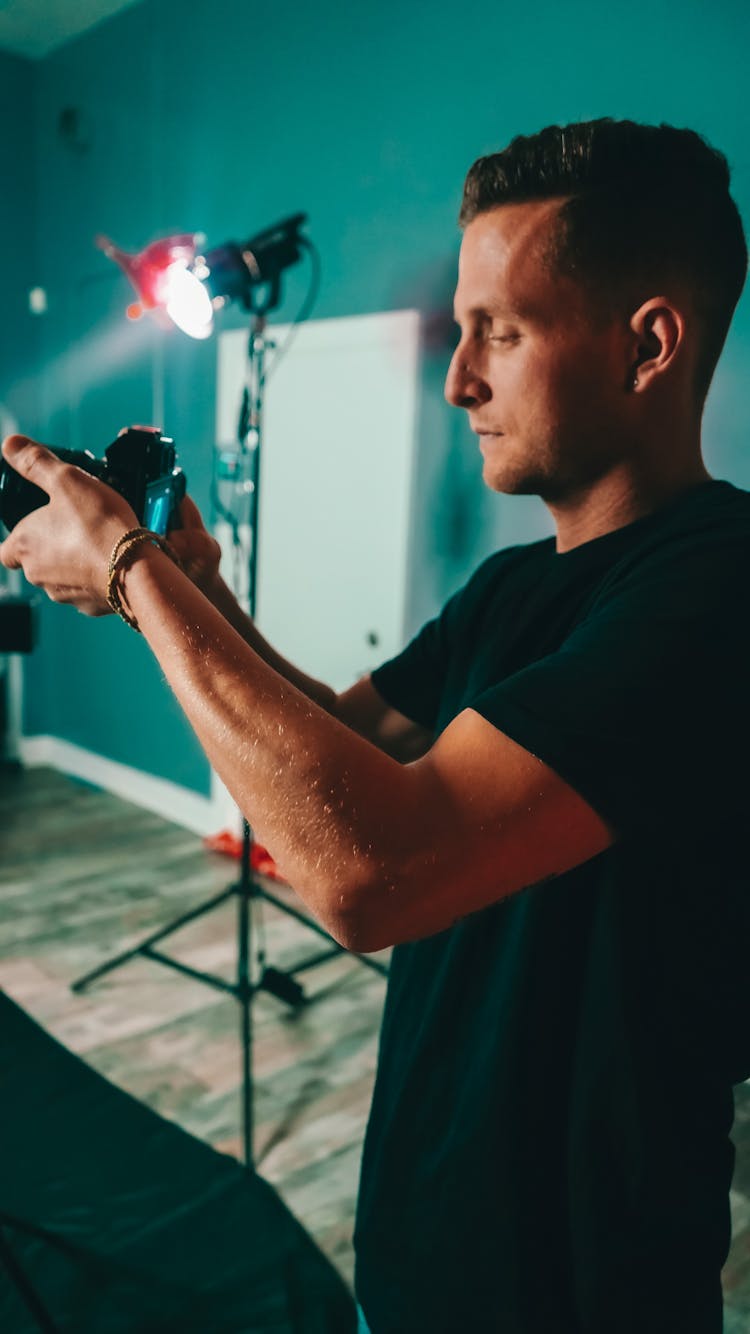 Focused Young Man Taking Pictures On Camera During Photo Session In Studio