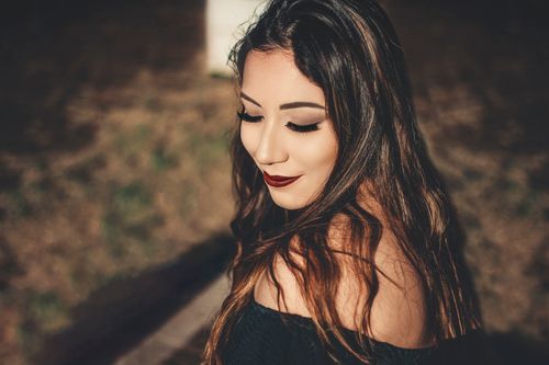Free Close-up of a young woman with elegant makeup and long hair outdoors in sunlight. Stock Photo