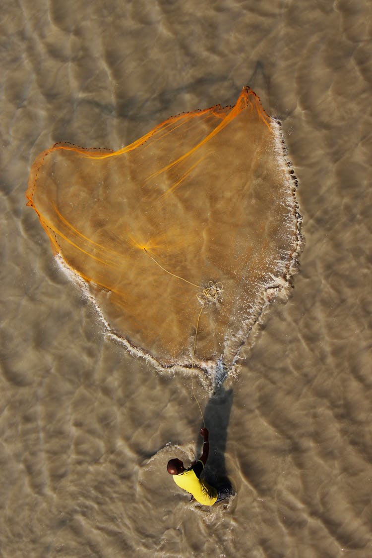 Anonymous Black Man Fishing In Sea With Net