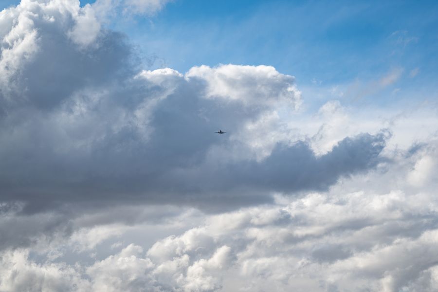 Airplane flying above the clouds in a blue sky