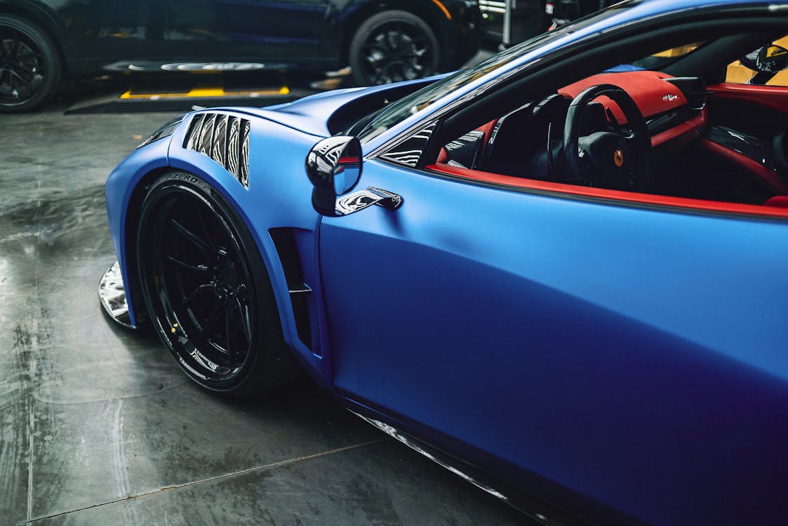 High angle of luxury blue sports car with red interior and curved details parked in modern garage