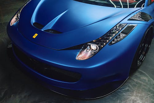 From above of stylish front bumper and glowing curvy headlights of modern luxury sports car