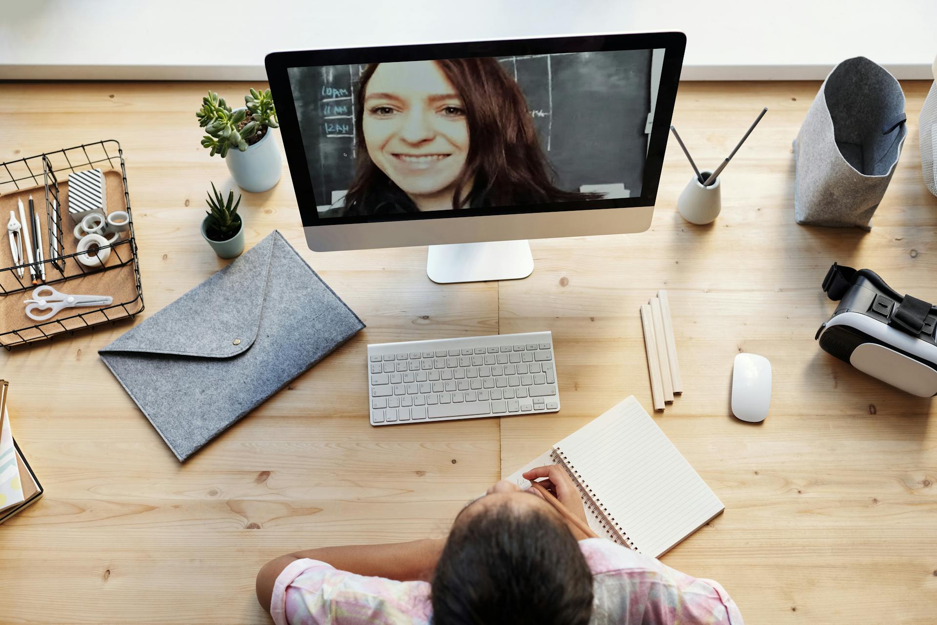 Teenager learning online at home with a tutor on a video call, using a computer.