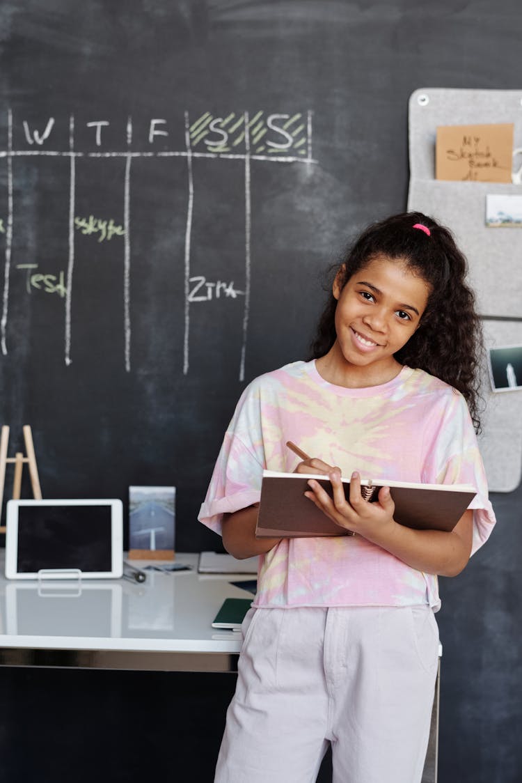 Girl In Pink And White Crew Neck T-shirt Holding Brown Notebook