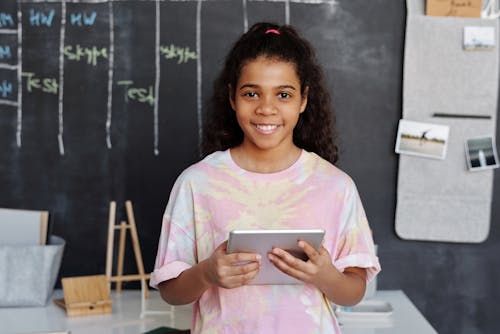 Woman in Pink Crew Neck T-shirt Holding Tablet Computer