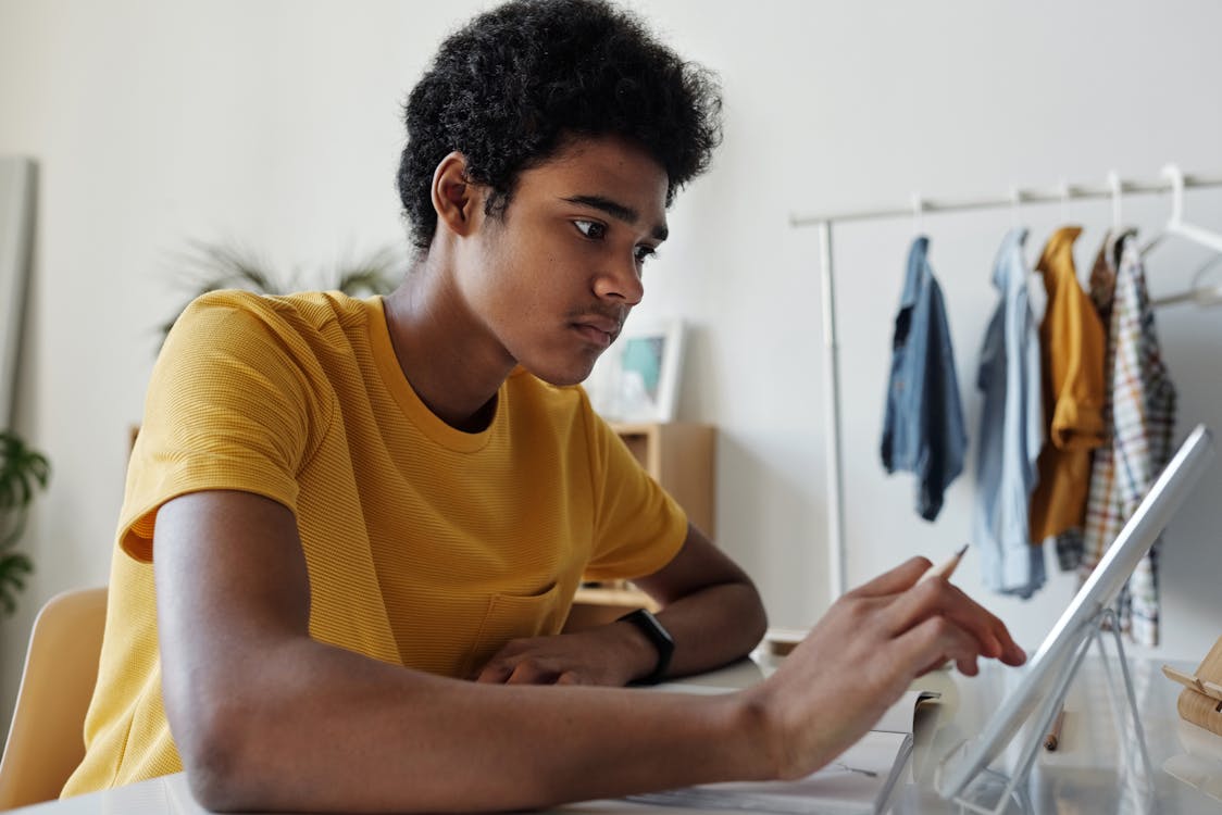 Man in Yellow Crew Neck T-shirt While Using Tablet