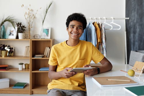 Boy in Yellow Crew Neck T-shirt Sitting on Chair