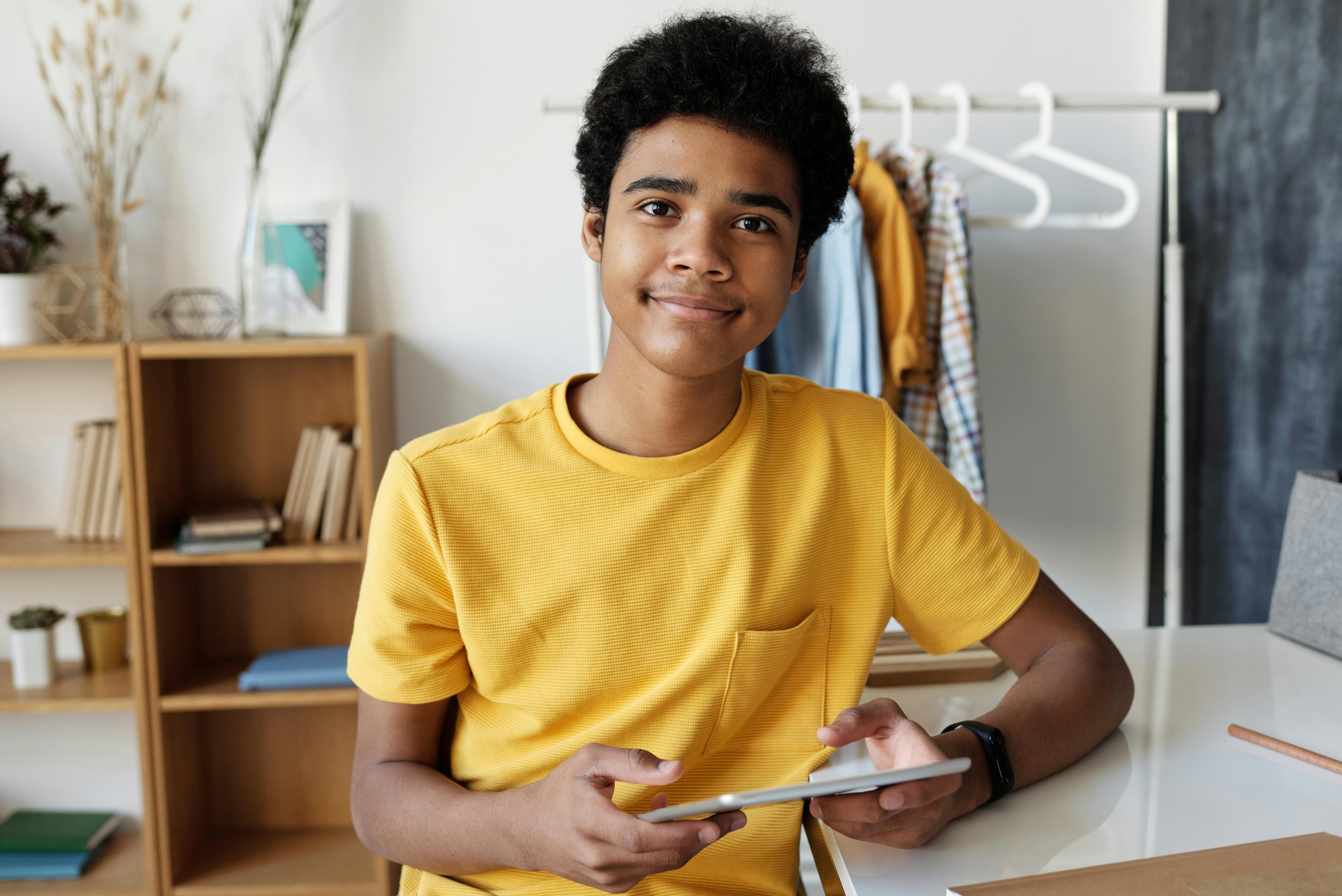 boy in yellow crew neck t shirt while holding tablet