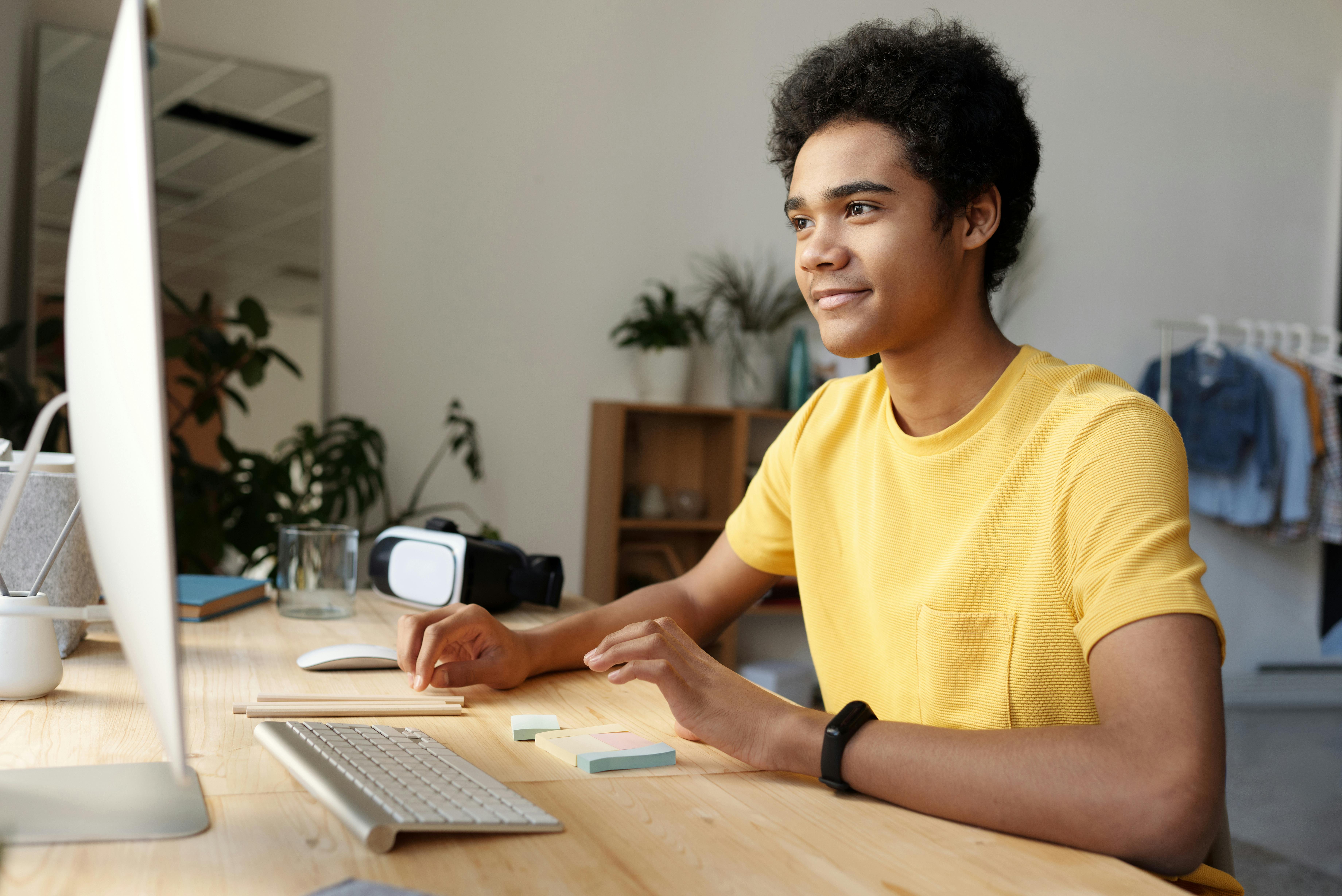 photo of boy wearing yellow shirt while using an imac