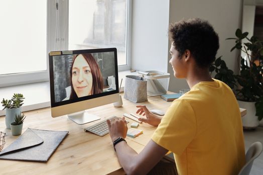 A young person participates in an online education session at their home using a desktop computer.