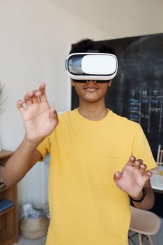 Teenager in yellow shirt using VR headset indoors for gaming.