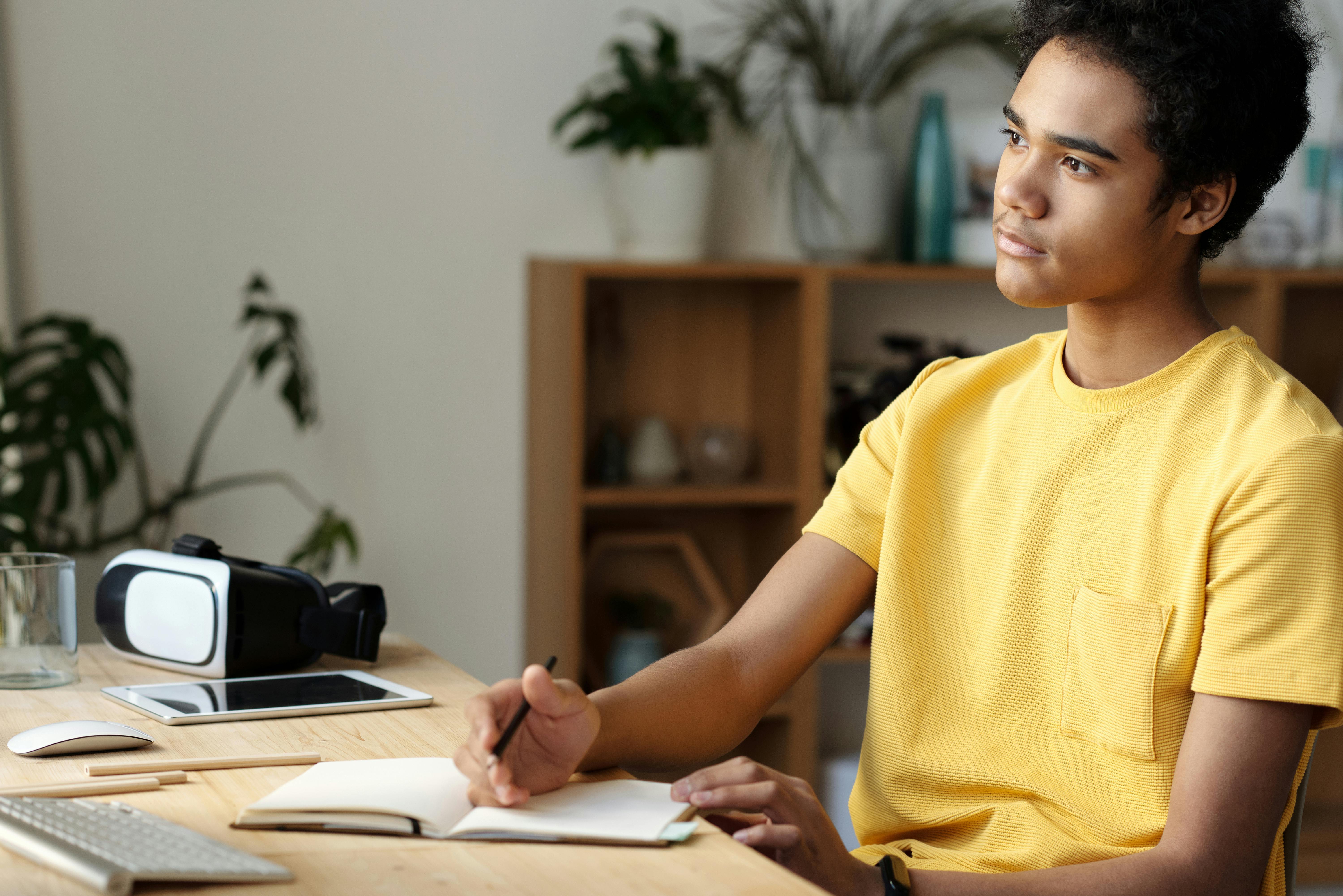 boy in yellow crew neck t shirt writing on white paper