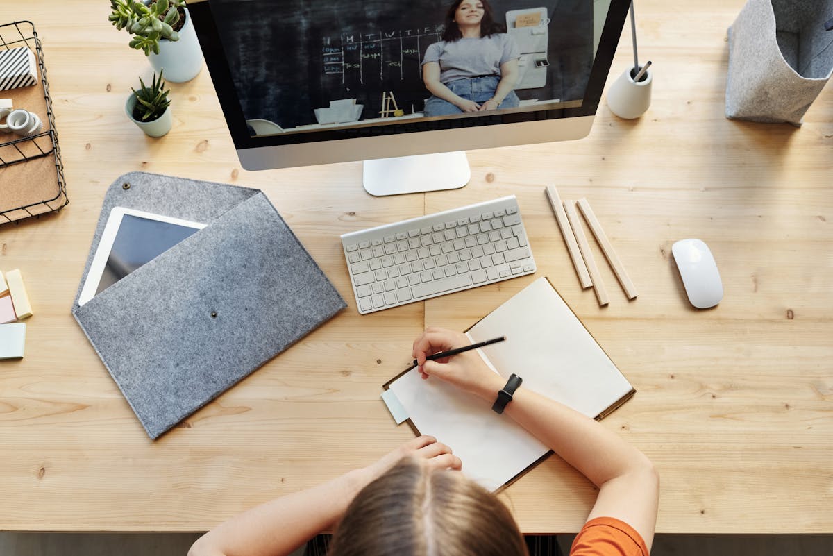 Person focusing on work at laptop with headphones on, sitting at a bright desk
