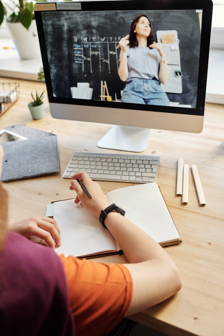 Person Using Silver Imac While Holding Pencil