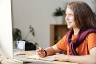 一位面带微笑的少女在家中利用现代技术进行在线学习