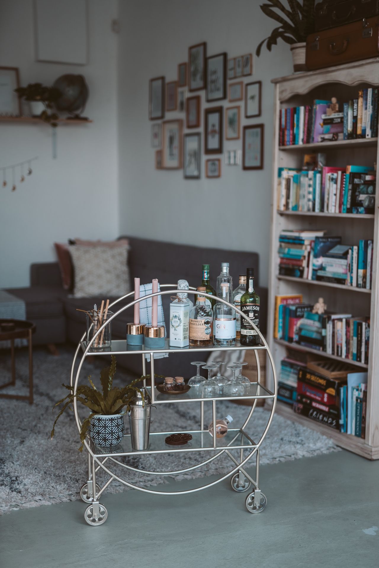 Round metal bar cart styled with liquor bottles, glasses, and a cocktail shaker