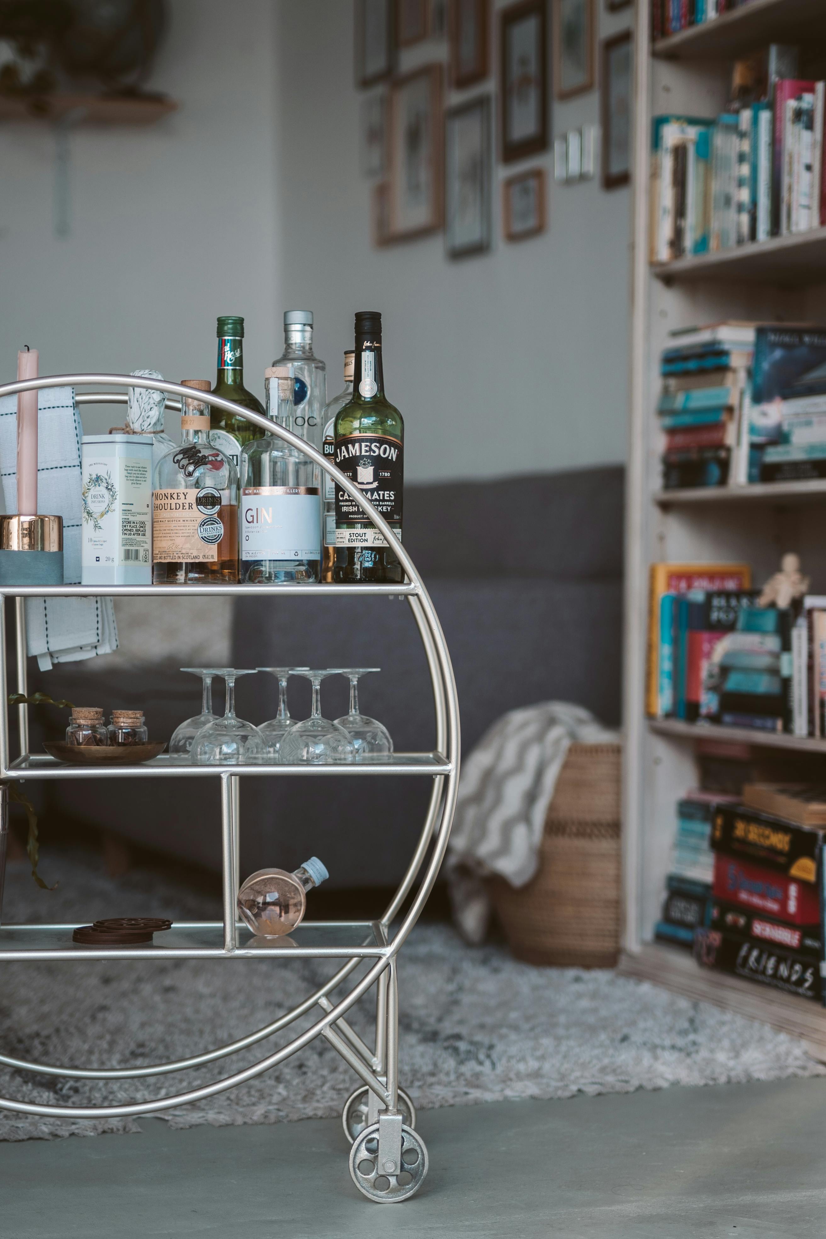 A styled drinks cart arranged with bottles and glassware in a cosy lounge