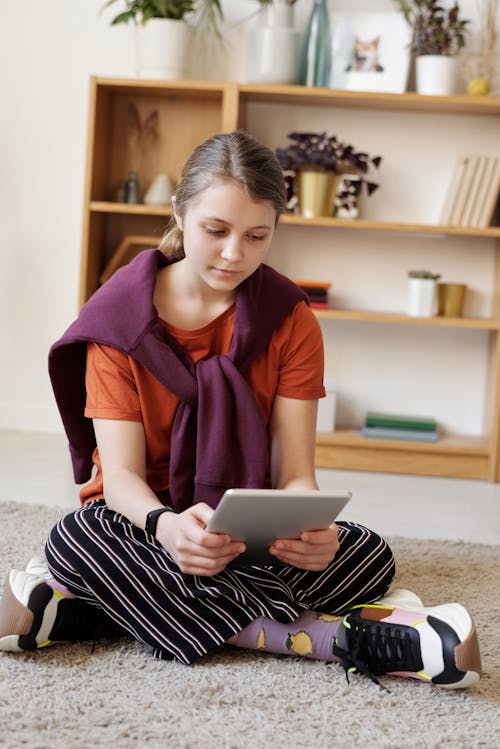 Free Photo of Girl Using Tablet While Sitting on Carpet Stock Photo