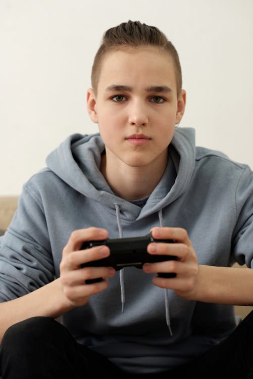 Boy in Gray Hoodie Holding Black Remote Controller
