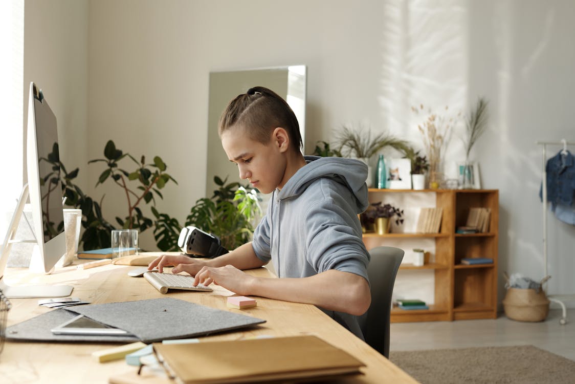 Free Boy in Gray Hoodie Sitting on Black Chair Stock Photo