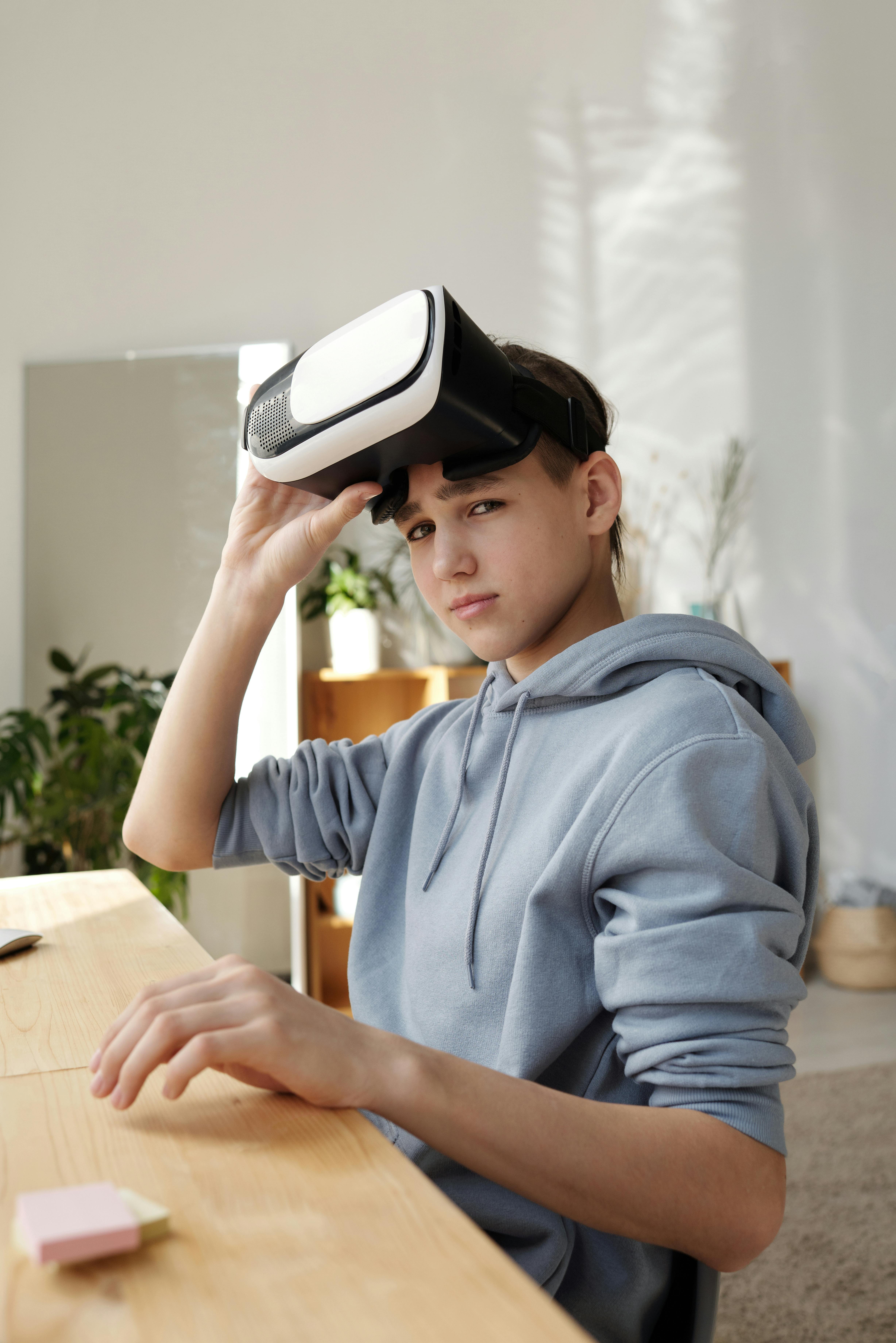 boy in gray hoodie while holding vr headset