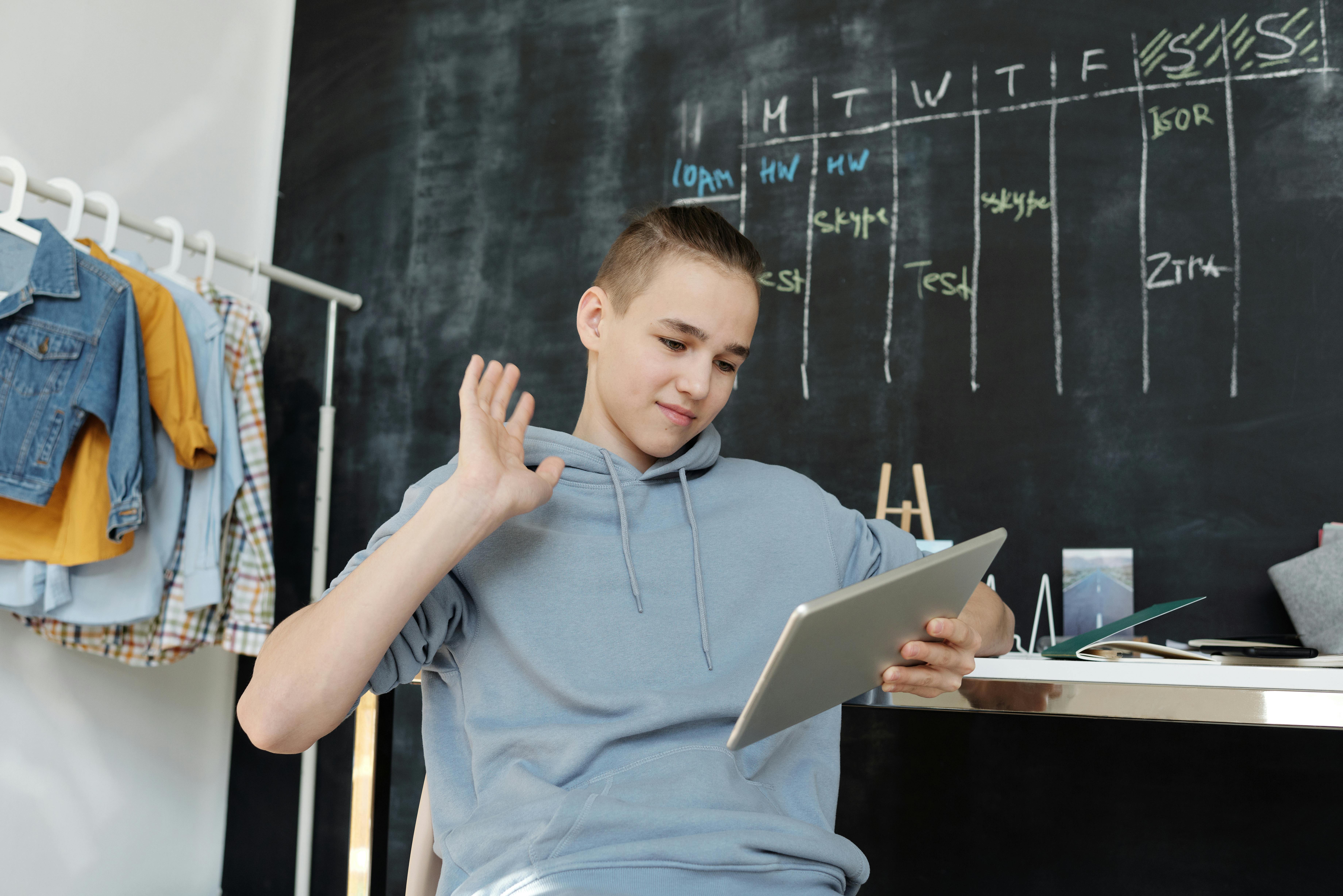 photo of boy wearing gray hoodie while using tablet