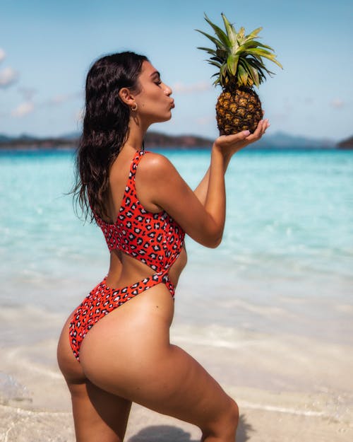 A Woman Holding a Pineapple at the Beach