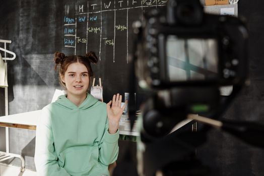 Woman in a mint green hoodie streaming from a home studio setup.